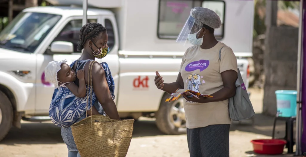 Um ativista da DKT apresenta a uma mulher da zona rural de Moçambique todas as suas opções de contraceptivos (contraceptivos orais, preservativos, injeções, DIUs e outros), às quais ela pode ter acesso imediato na clínica móvel, se assim o desejar.